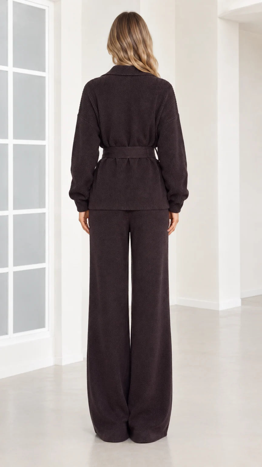 Back view of woman wearing dark brown ribbed knit belted top and wide-leg trousers
