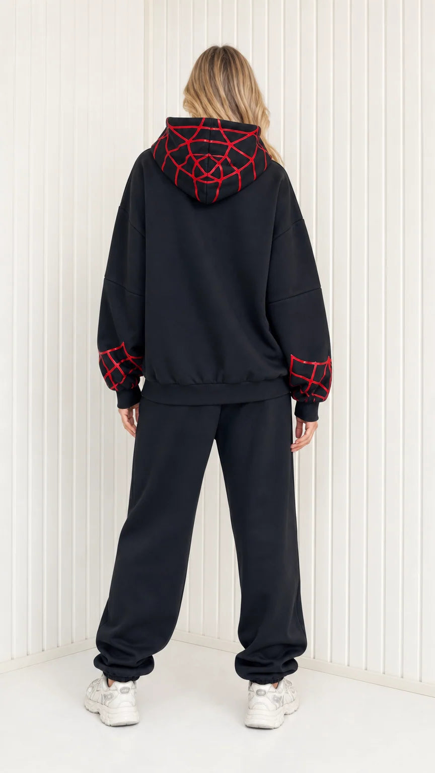 Back view of model showing graphic web details on hoodie of black sweatsuit set