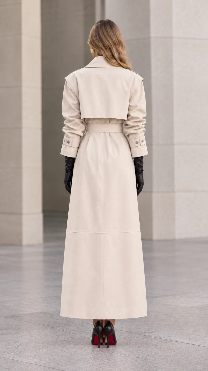 Back view of woman wearing cream maxi trench coat showing back storm flap and vent