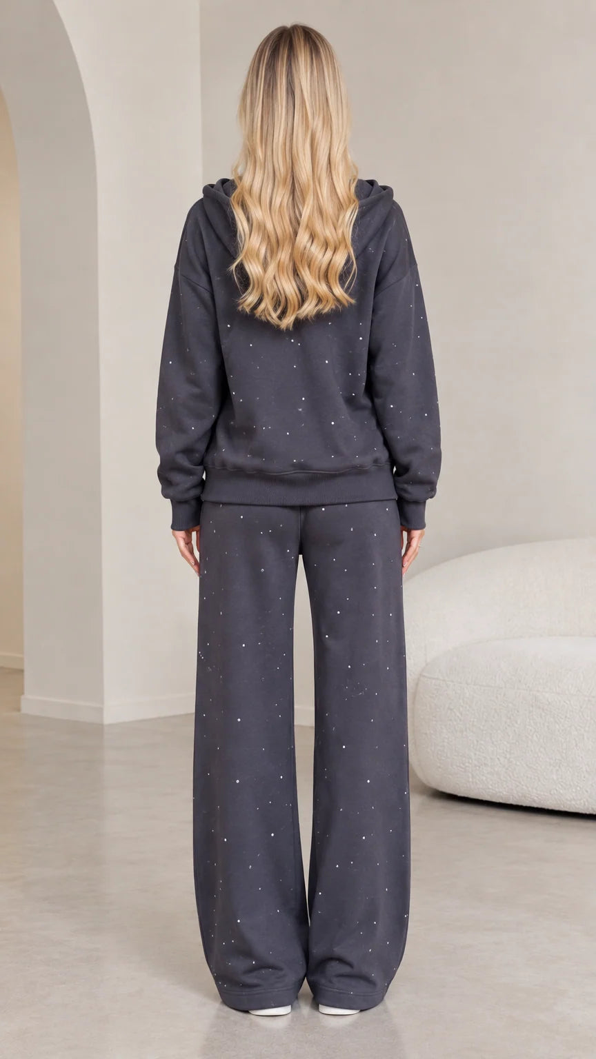 Back view of model wearing dark grey rhinestone hooded sweatshirt and wide-leg lounge pants