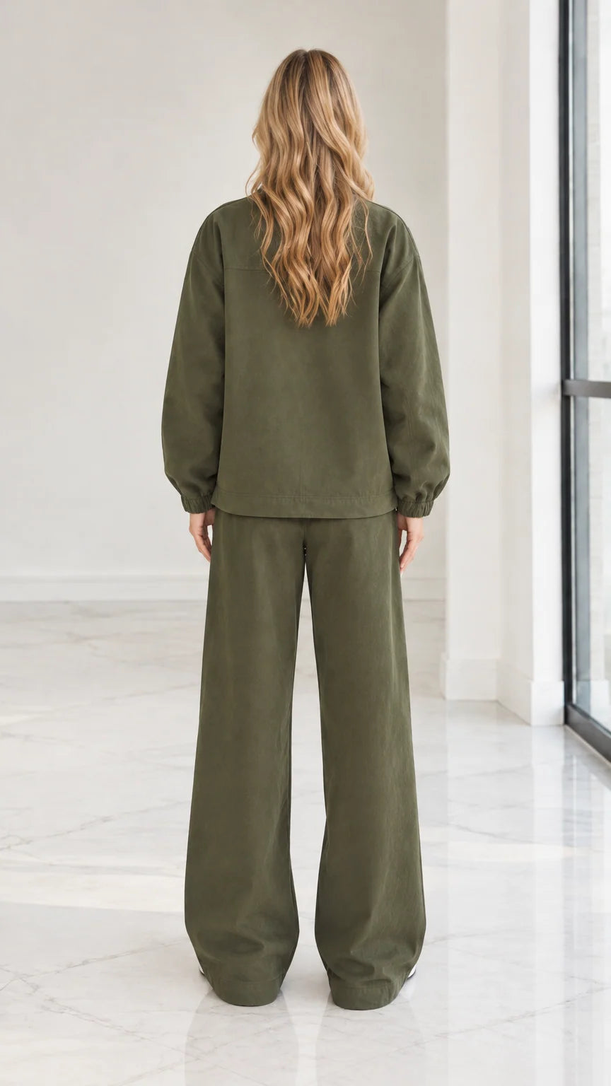 Back full view of woman wearing olive green 2-piece zip jacket and wide leg pants set