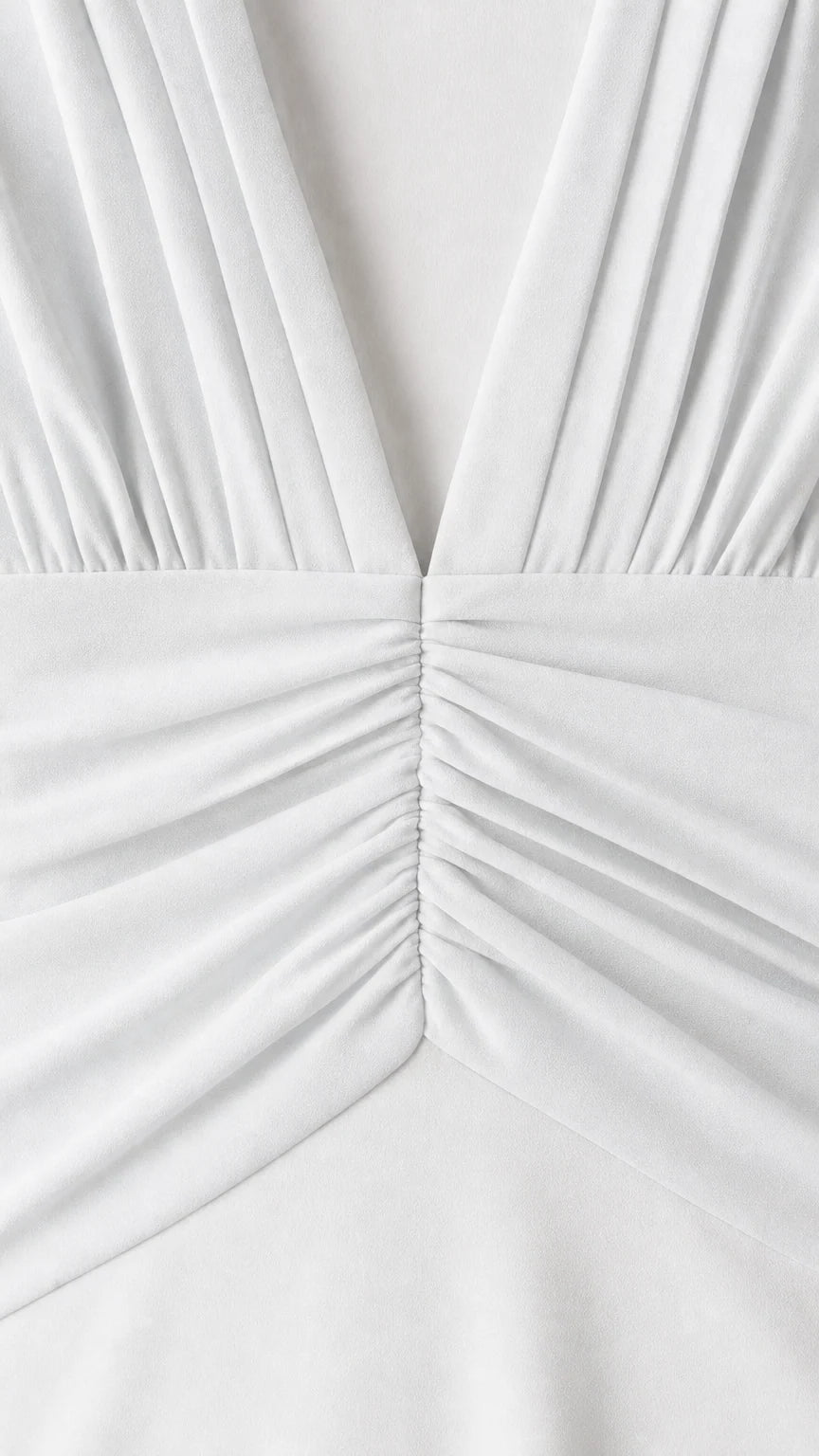 Close-up detail of pleated V-neck and ruched waist on white dress