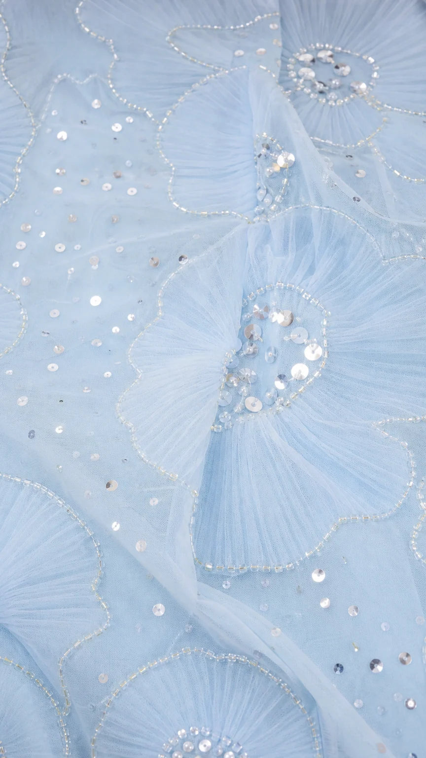 Close-up of light blue mesh fabric with sequin floral embroidery