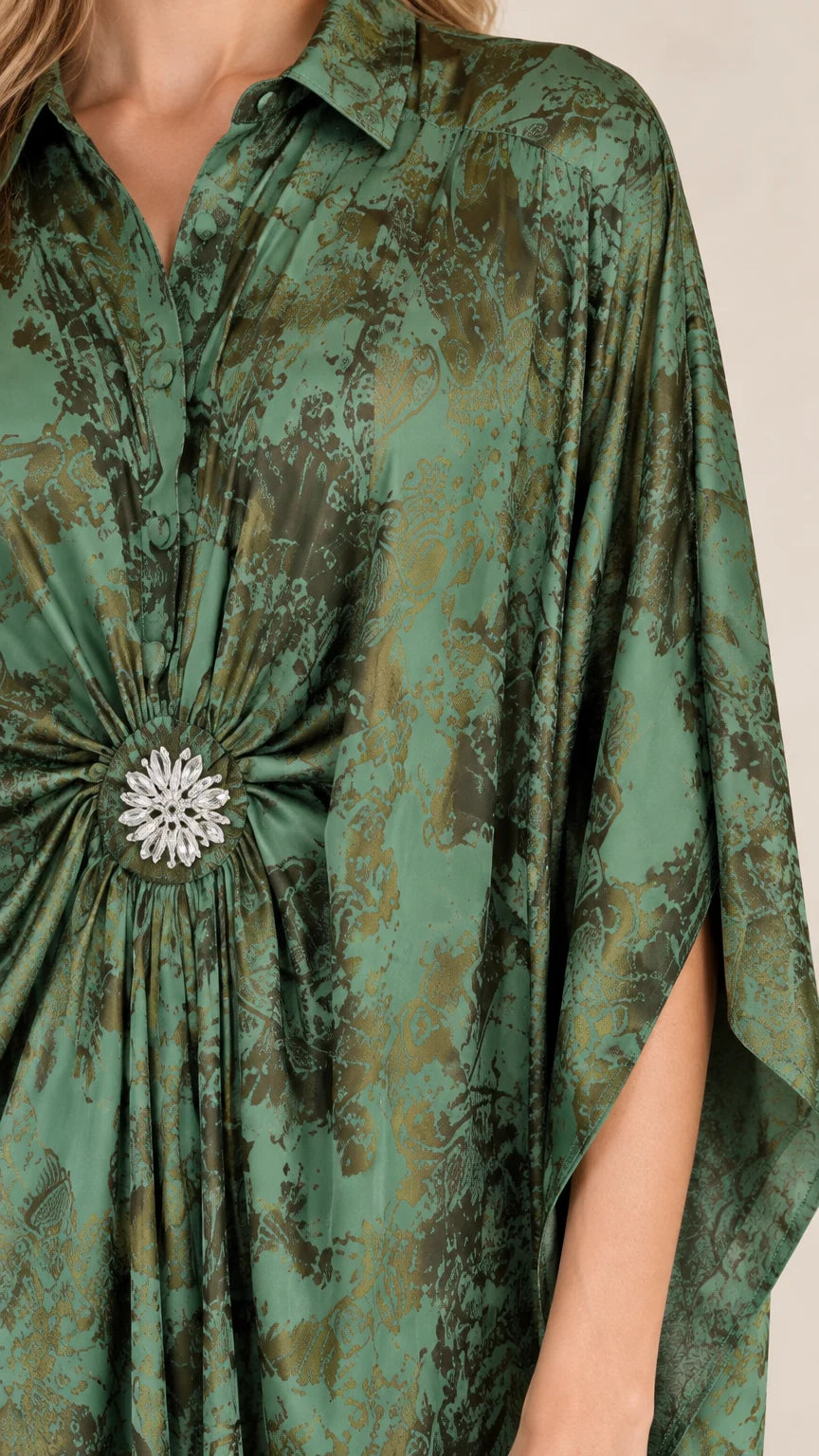 Close-up detail of collared neckline and sparkling crystal waist brooch on green printed kaftan