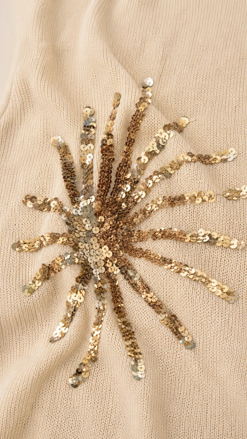 Close-up detail of gold sequin sunburst embroidery on fabric