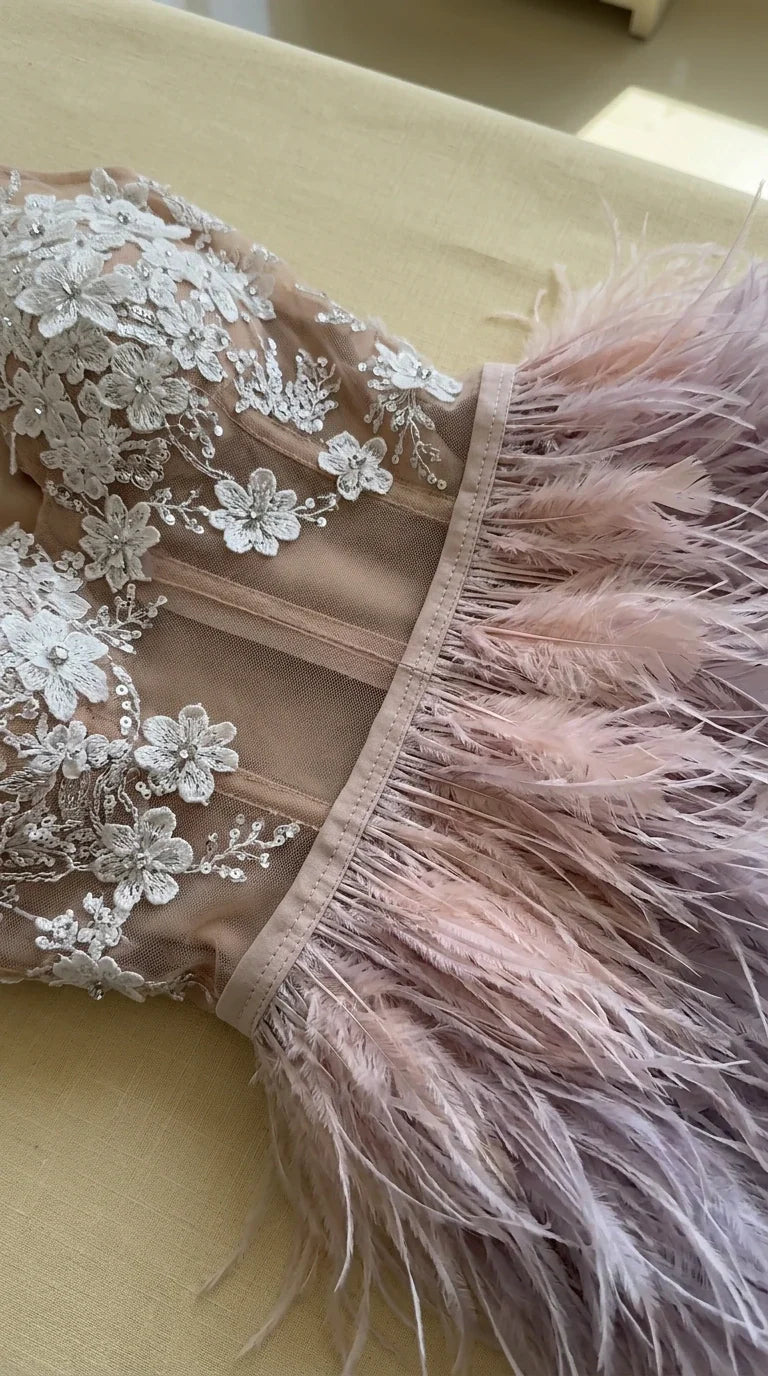 Close-up detail of sheer corset boning, 3D floral embroidery, and lush feather trim