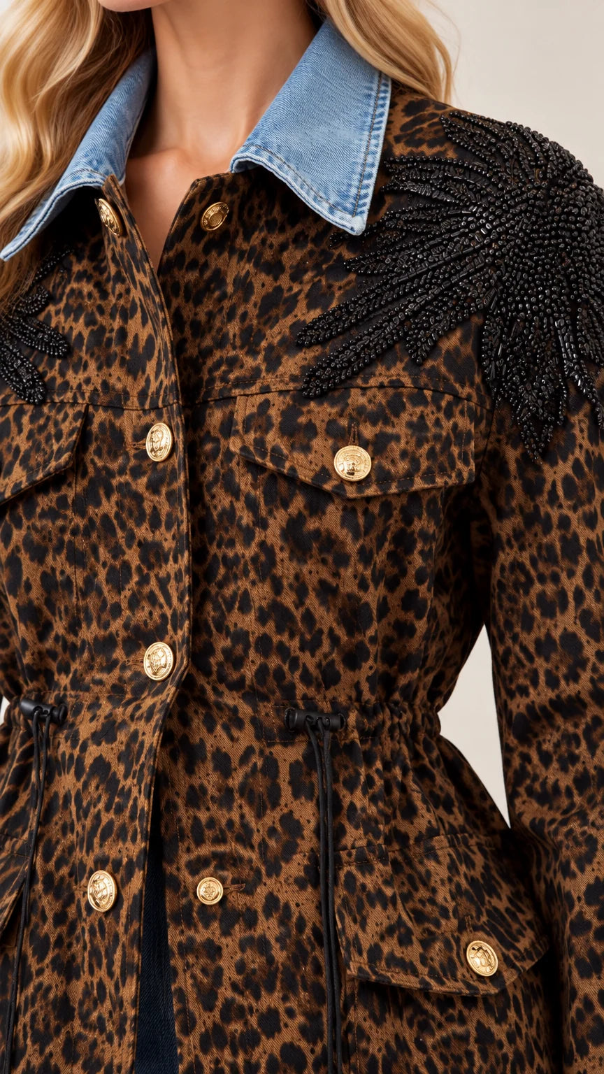 Close-up detail of denim collar, gold buttons, and black beaded shoulder fringe on leopard jacket