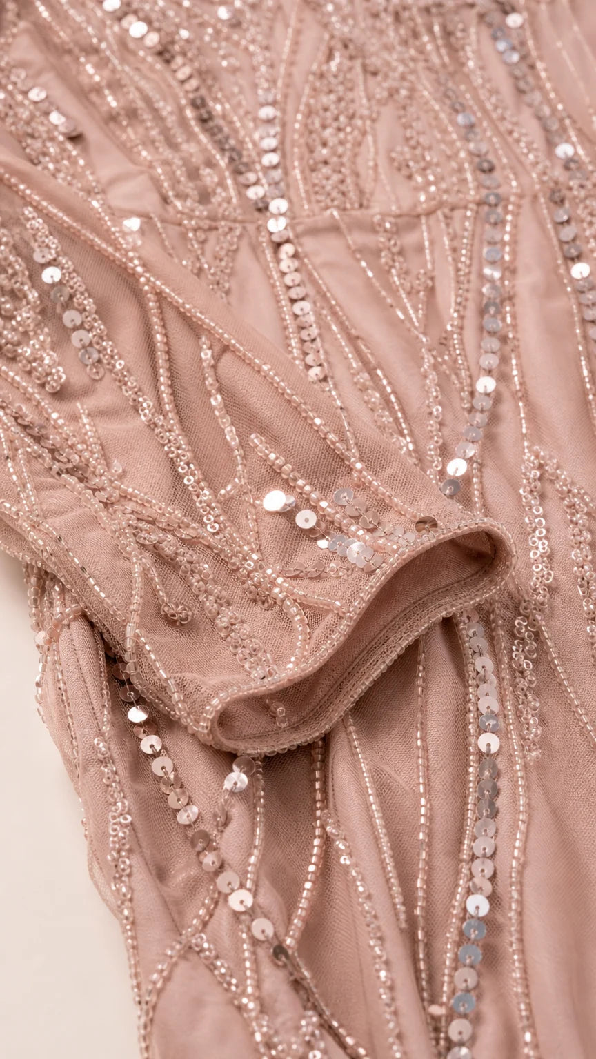Close-up detail of dusty rose mesh sleeve showing intricate sequin and bead embellishments