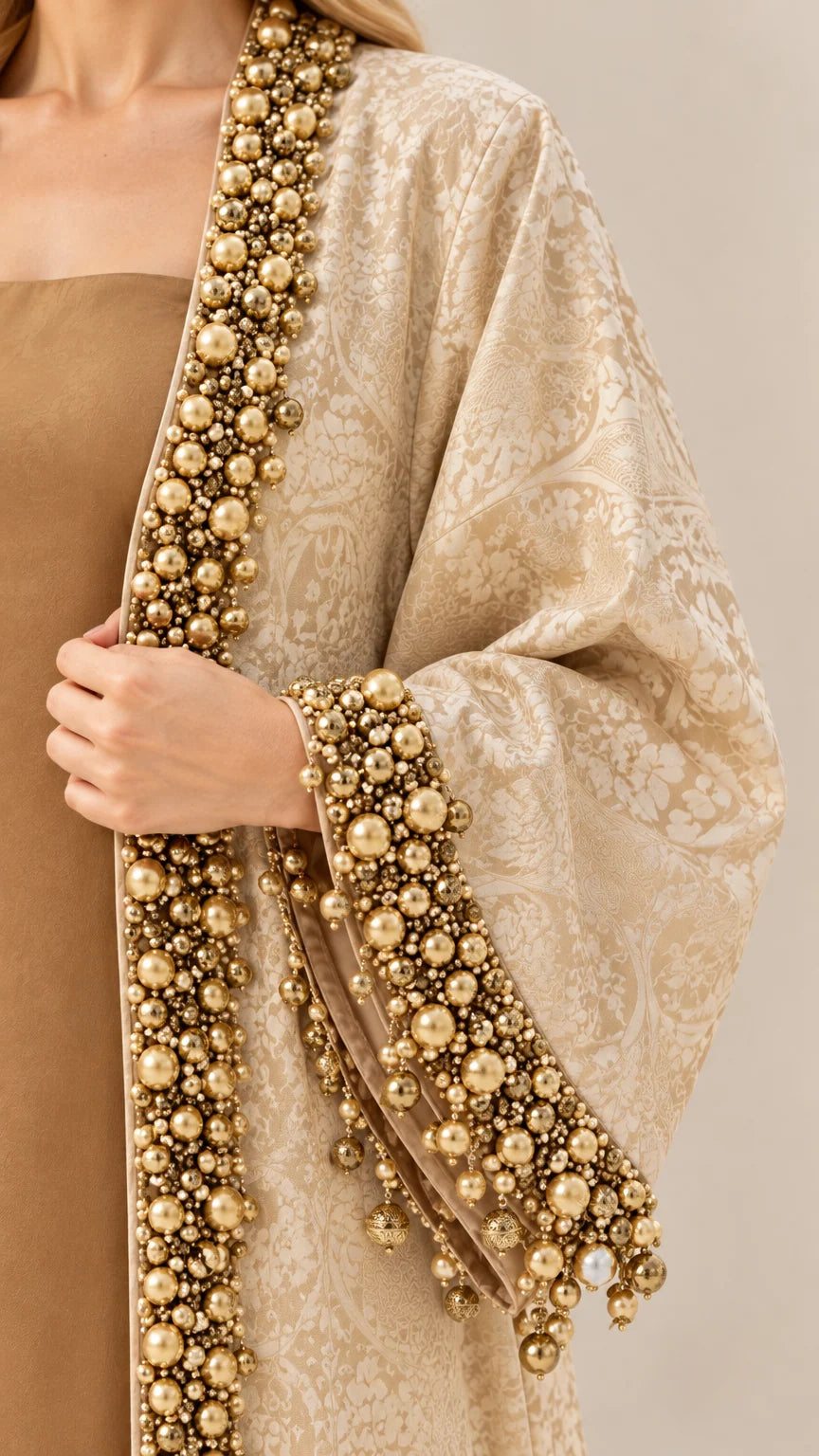 Close-up detail of luxury gold beadwork and faux pearl trims on jacquard sleeve and front edge