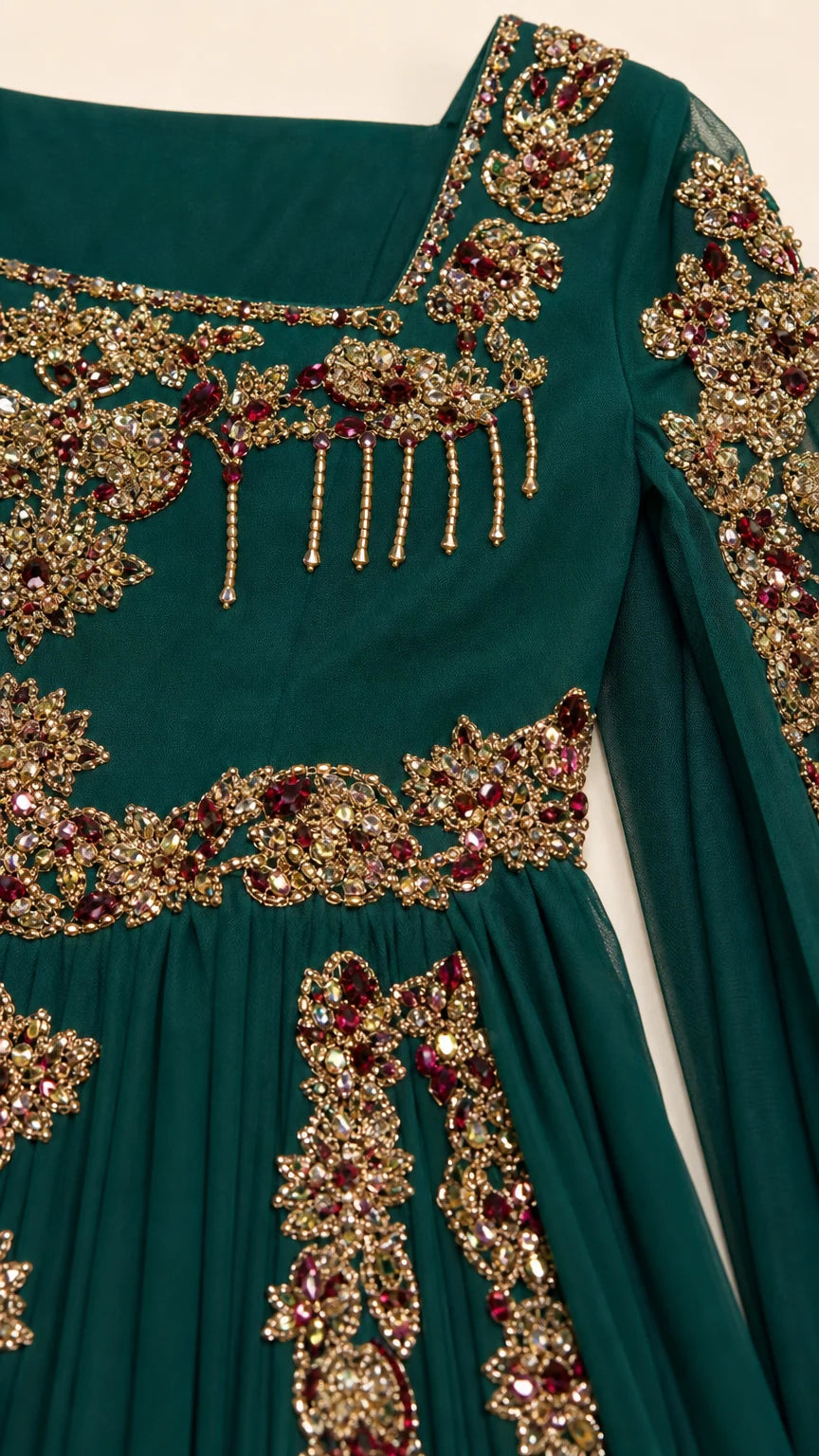 Close-up detail of ornate gold embroidery and beading on dark green chiffon