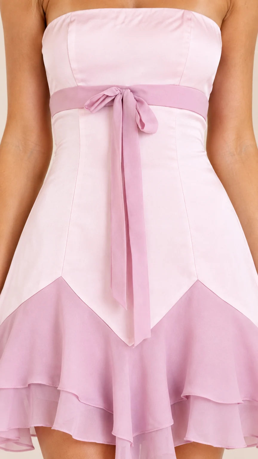 Close-up detail of bodice, bow sash, and tiered chiffon ruffle skirt on pink dress