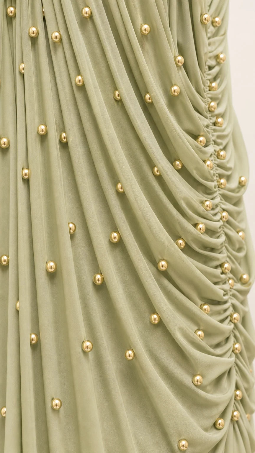 Close up detail of gathered fabric with gold-tone beaded embellishments