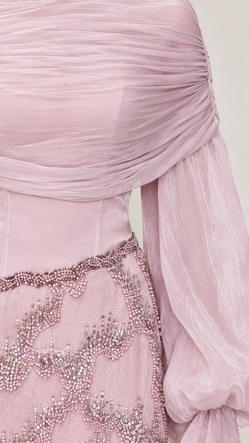 Close-up detail of pleated drape neckline and intricate beadwork on skirt waistband