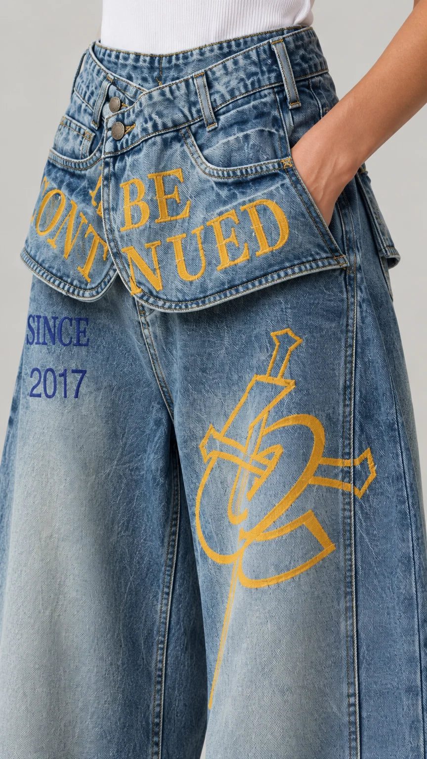 Close-up detail of the graphic print and fold-down waistband on blue denim