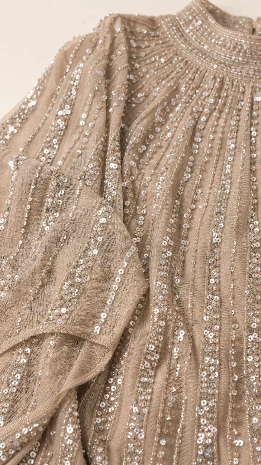 Close-up detail of champagne pleated mesh fabric with linear sequin stripes