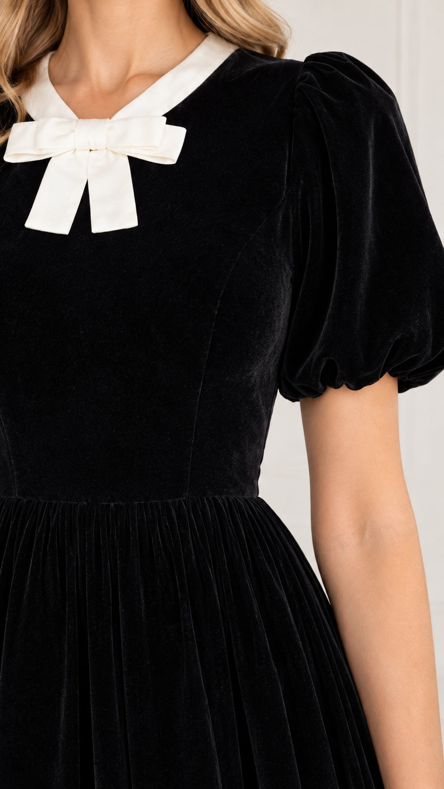 Close-up of contrast white bow collar and puff sleeve on black velvet dress