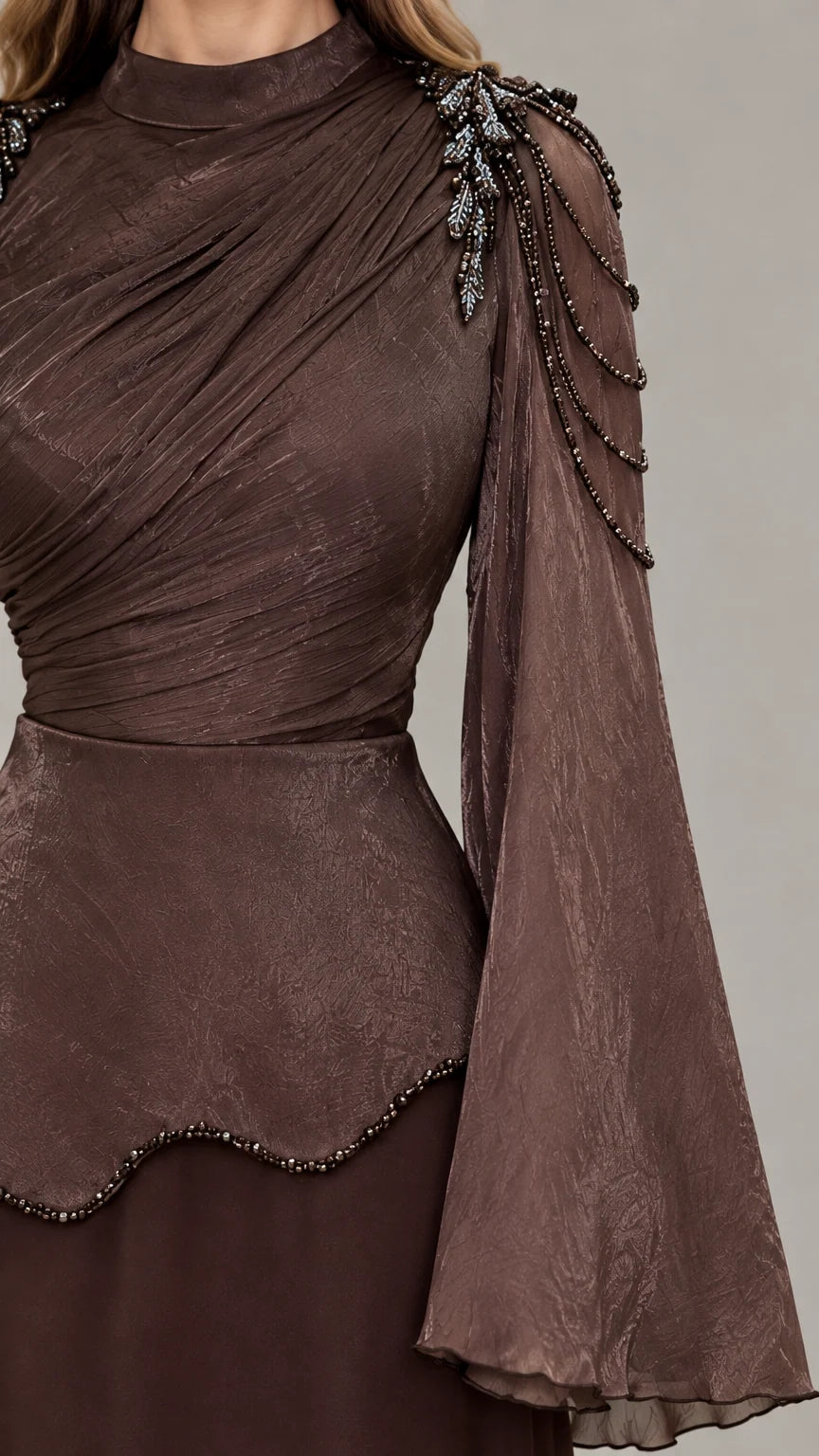 Close-up of ruched neckline, beaded shoulder detail, and textured bell sleeves on brown gown