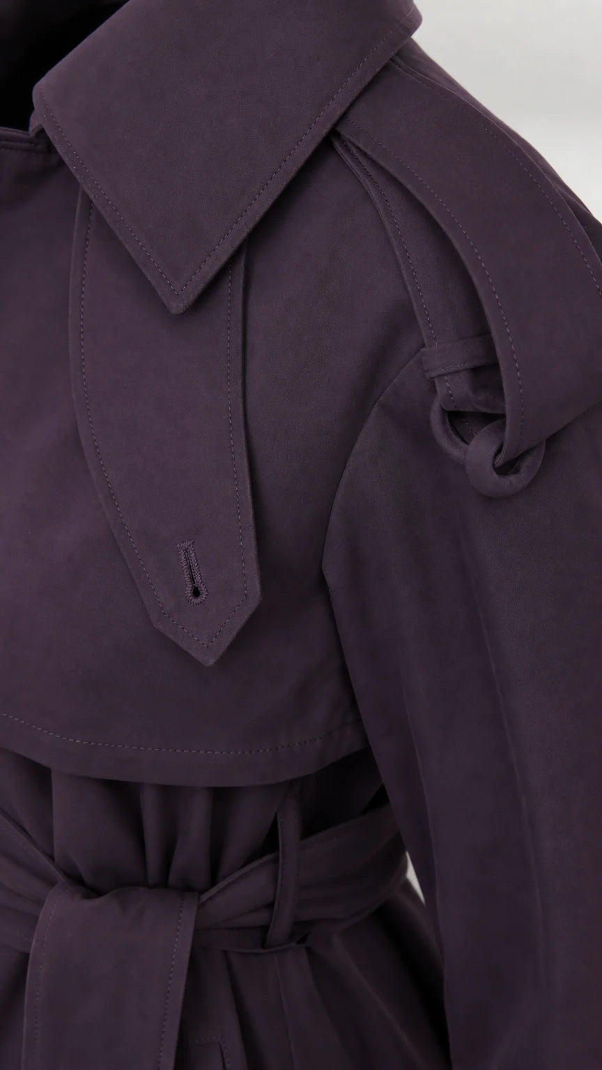Close-up detail of deep purple trench coat shoulder epaulet tab and collar