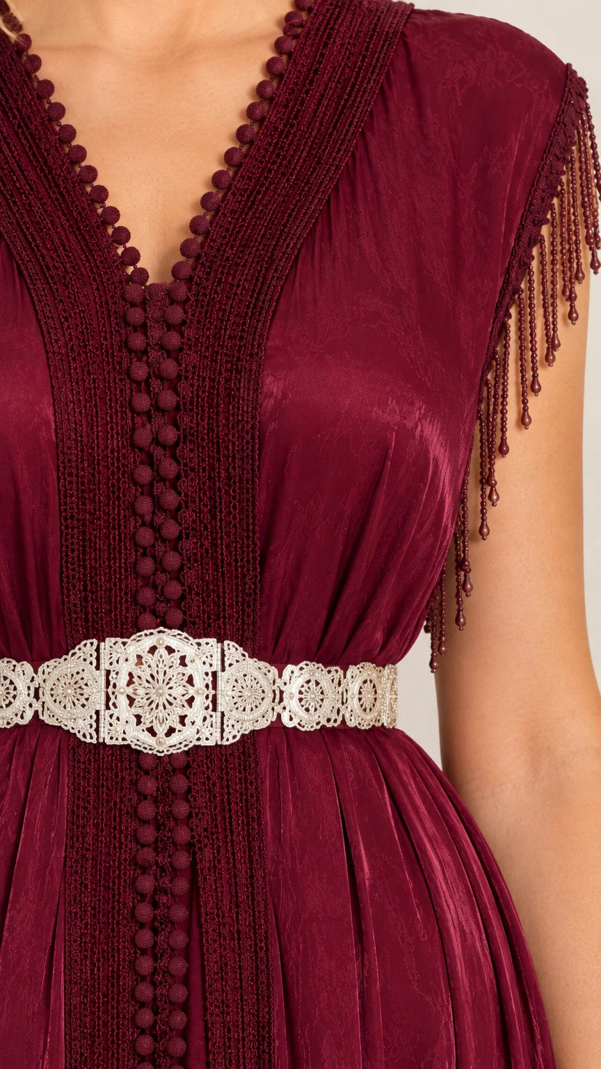 Close up view of burgundy dress bodice with textured neckline trim and filigree belt