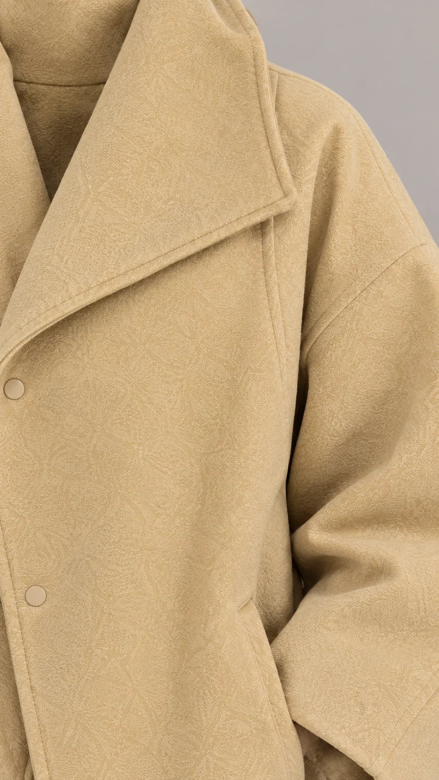 Close-up detail of textured camel wool-touch fabric and snap closure collar