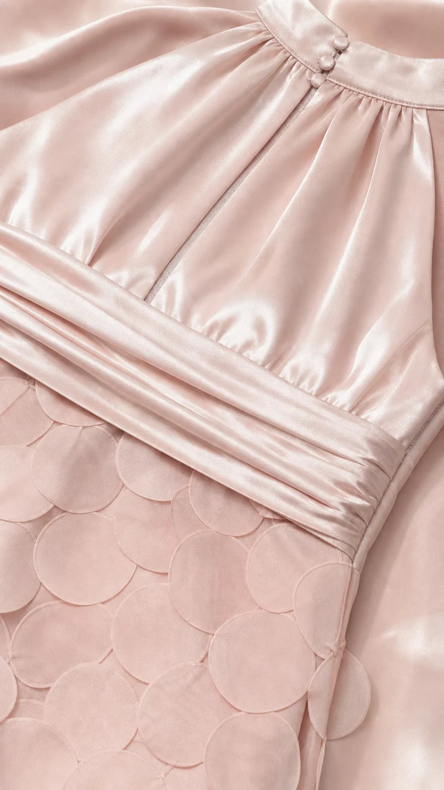 Close-up detail of blush pink pleated satin bodice and ruched waistband with circular disc texture