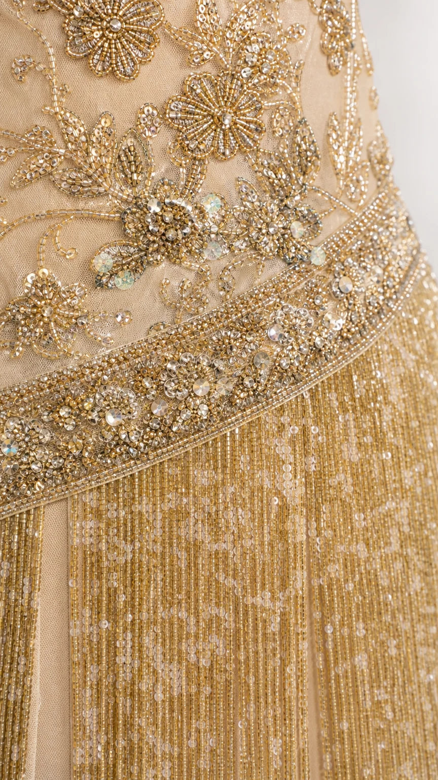 Close-up detail of gold floral beadwork, sequins, and layered fringe
