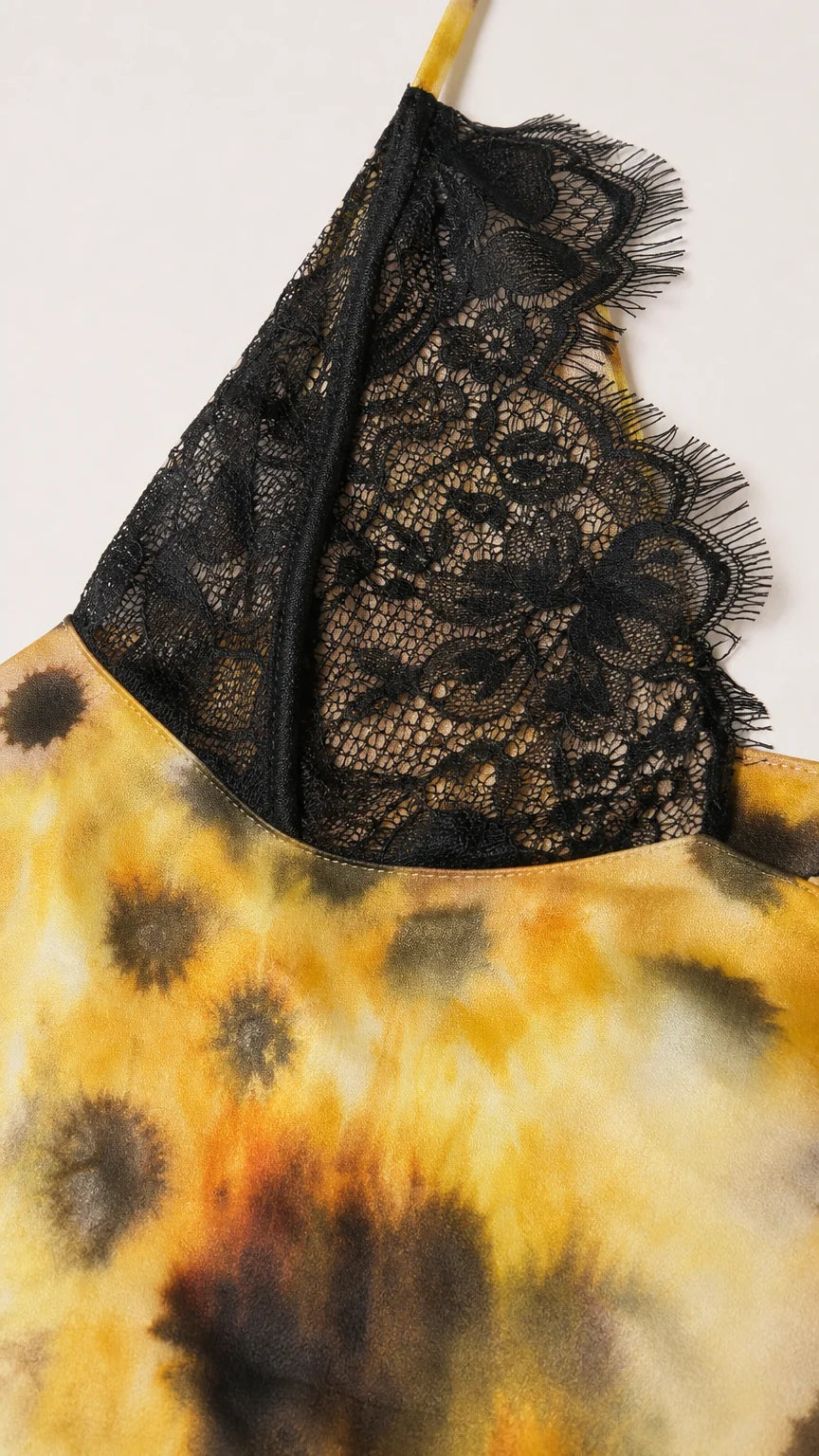 Close-up detail of black floral lace cup on yellow tie-dye fabric