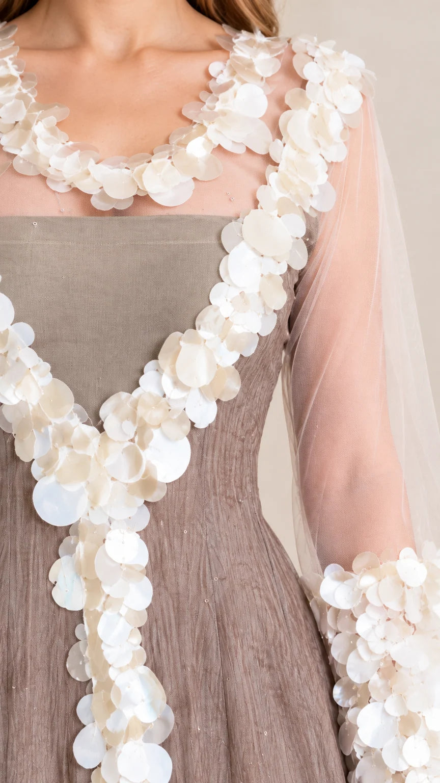 Close-up detail of sheer neckline, bodice, and sleeves adorned with dimensional circular petal paillettes