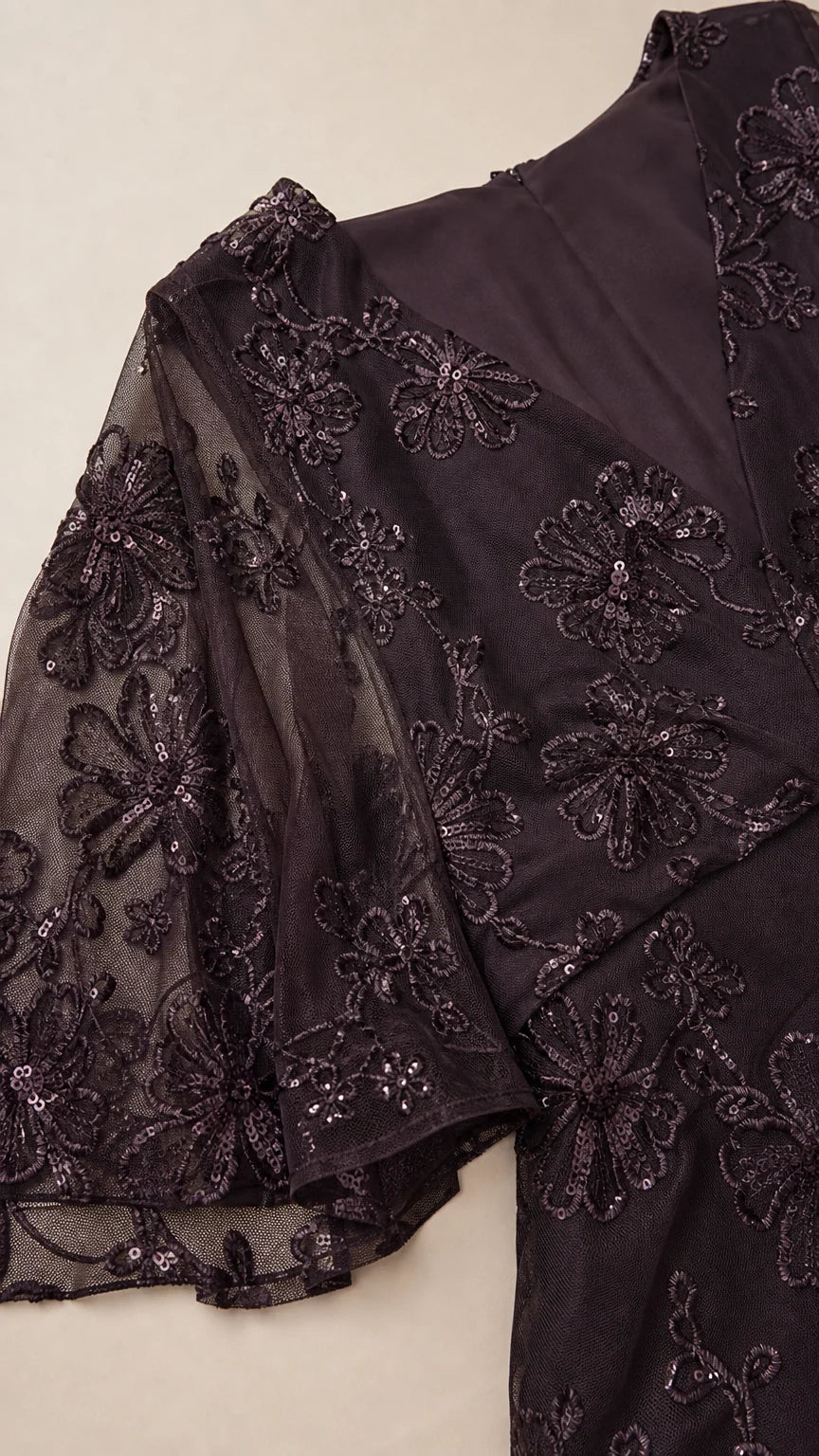 Close-up detail of floral sequin embroidery and sheer flutter sleeve on dark plum gown