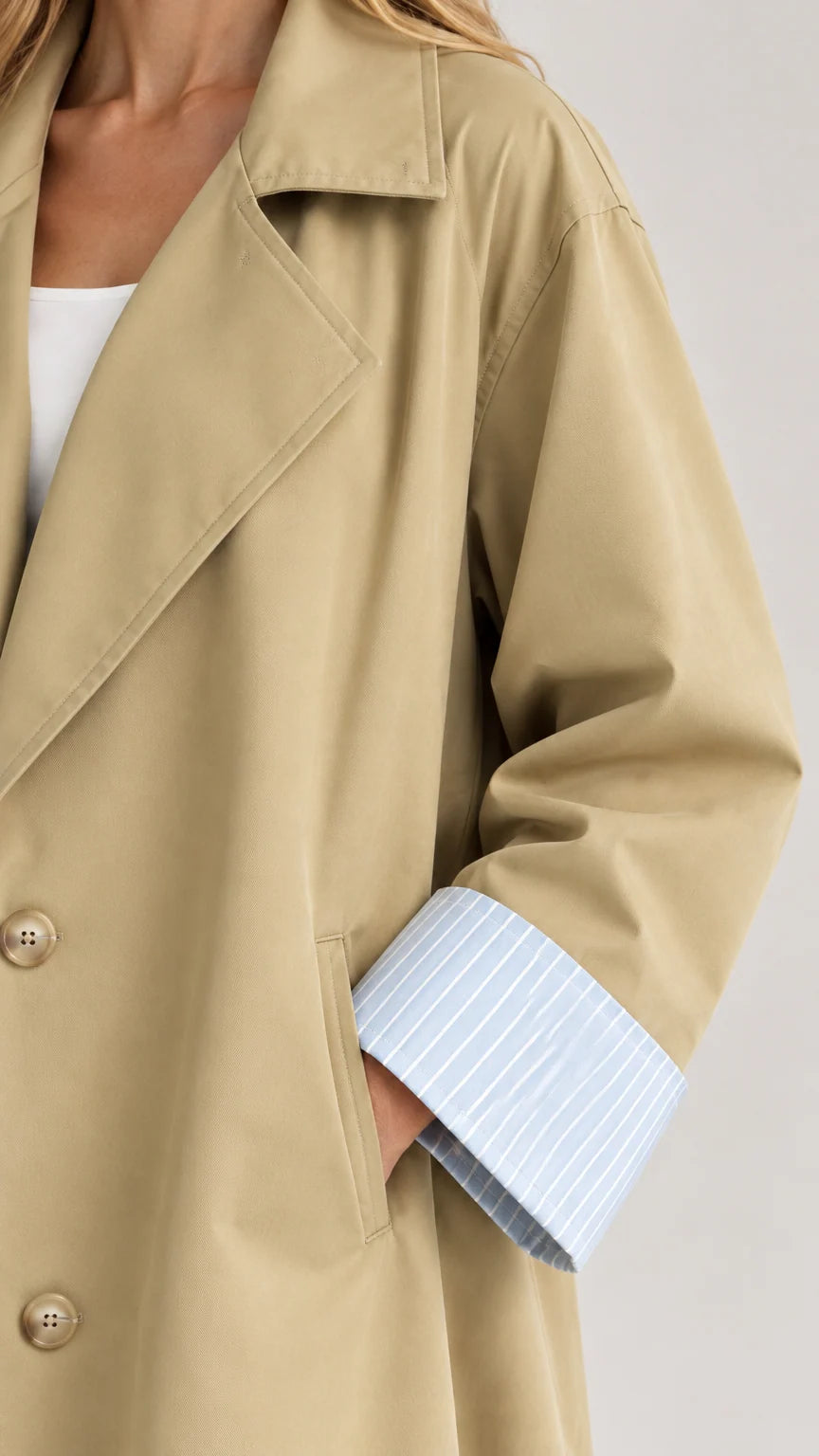 Close-up detail of khaki trench coat collar, front buttons, and striped sleeve cuff