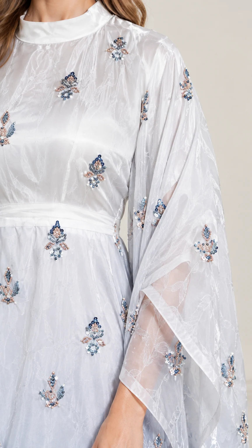 Close-up detail of sheer fabric and delicate floral embroidery on neckline and sleeve