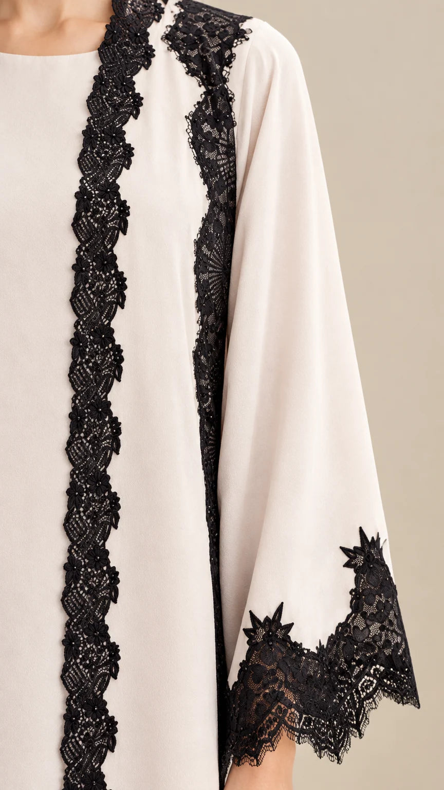 Close-up detail of delicate black floral lace trim on cream sleeve and bodice