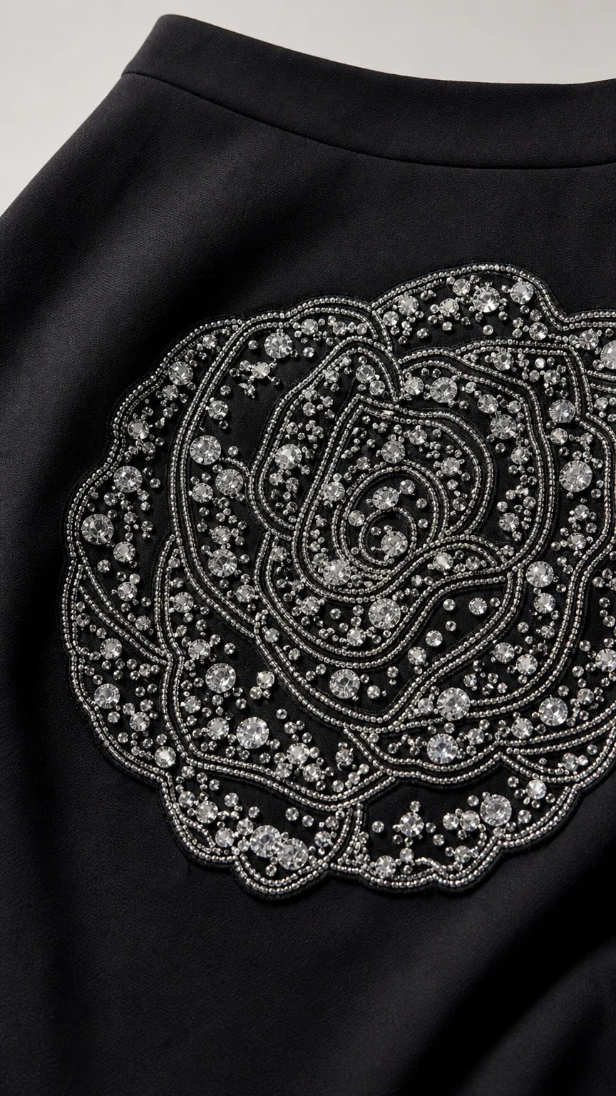 Close-up of intricate rhinestone and bead rose applique on black skirt