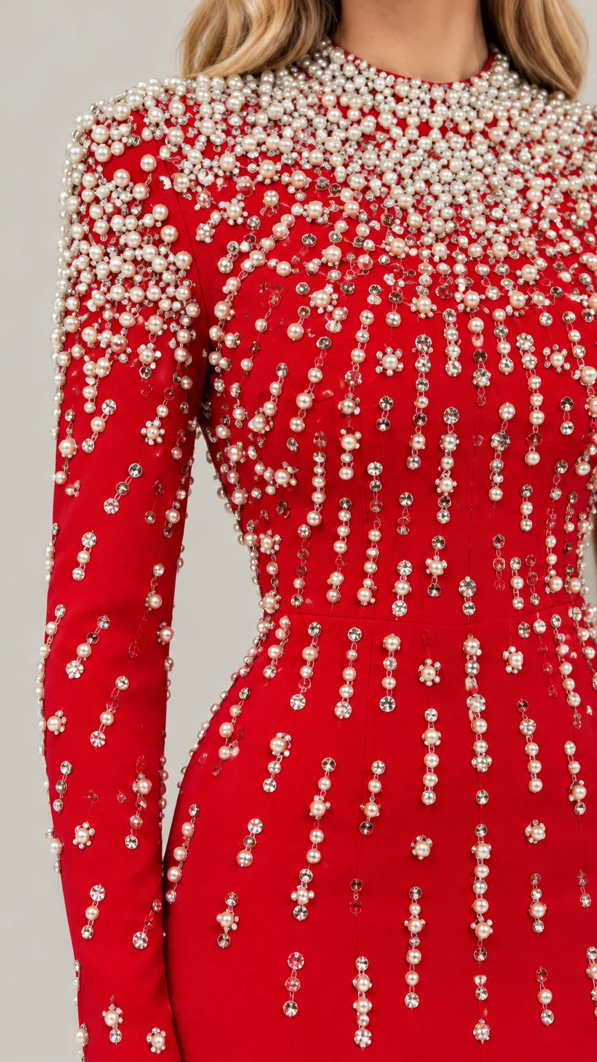 Close-up detail of cascading pearl and rhinestone embellishments on red fabric