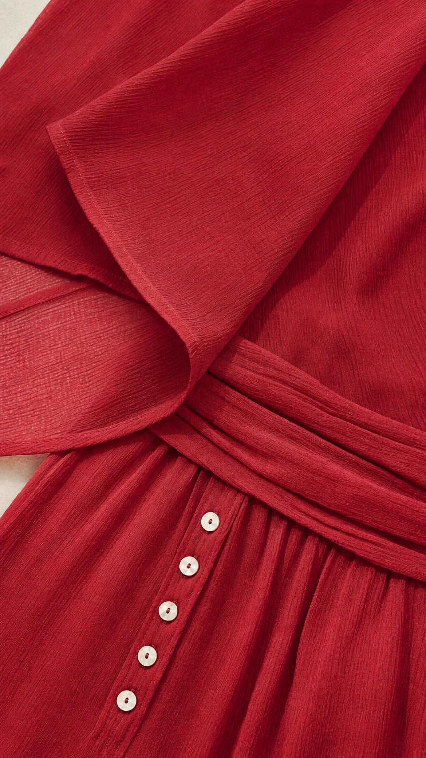 Close-up of red textured fabric, button details, and waistband