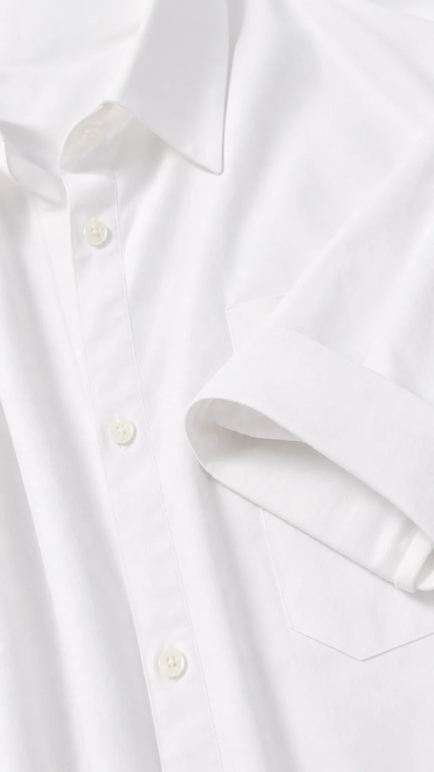 Close-up detail of collar, button placket, and pocket on white shirt dress