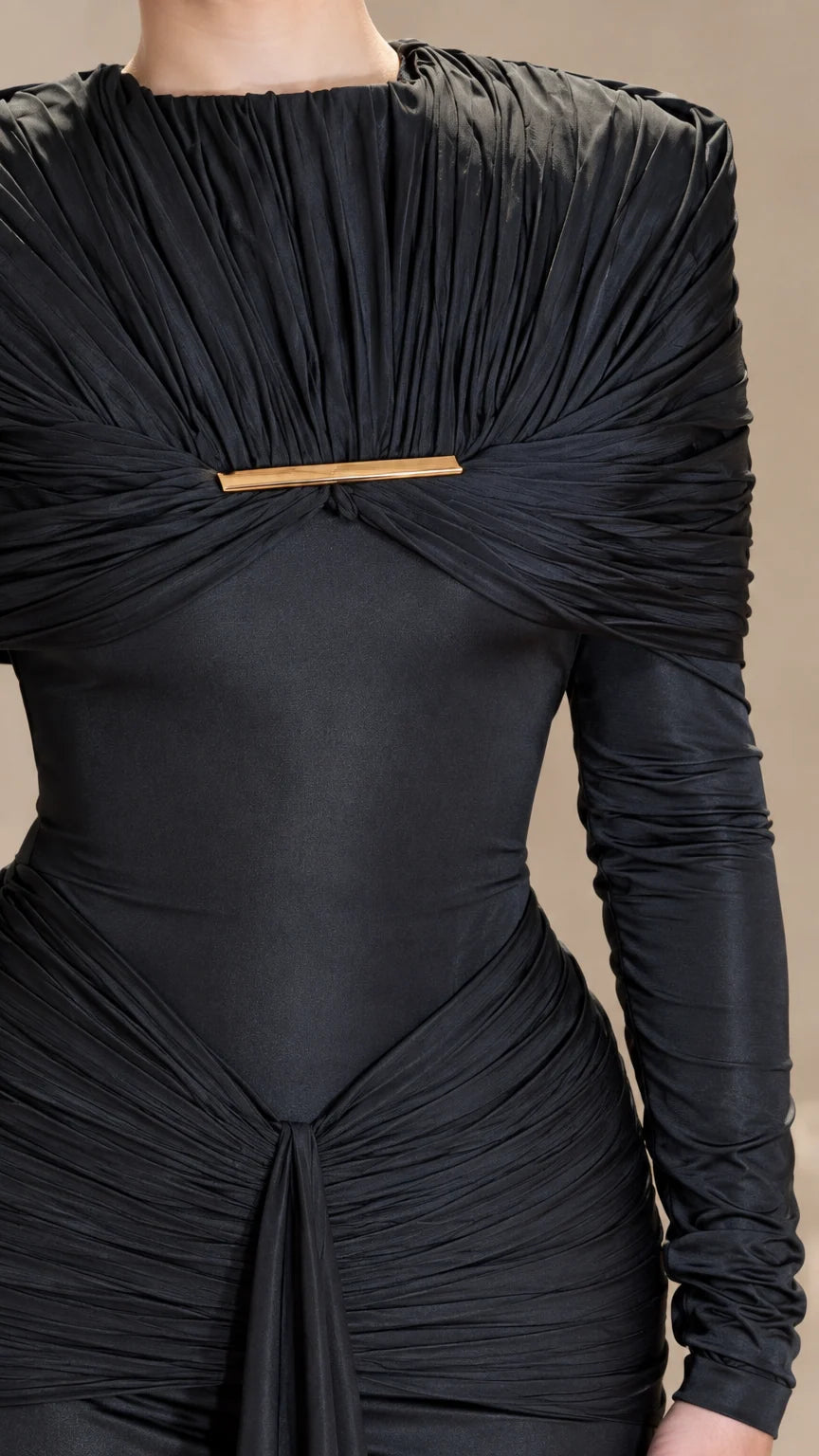 Close-up detail of black pleated cape bodice with central gold bar hardware