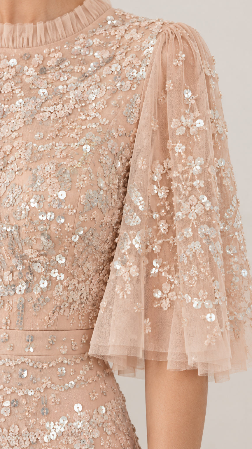 Close-up detail of champagne tulle fabric with floral sequin embroidery and ruffled neckline